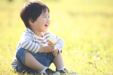 Çocuk parkta dondurma yiyor. 