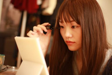 Asyalı kız evde makyaj yapıyor. 