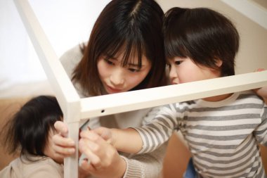 Çocuklu Asyalı kadın yeni evinde masa topluyor.