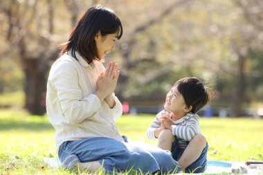 Asyalı anne oğluyla parkta yemek yiyor.