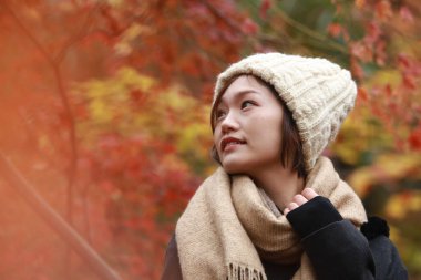 Sonbahar parkında poz veren Asyalı genç kadının portresi. 