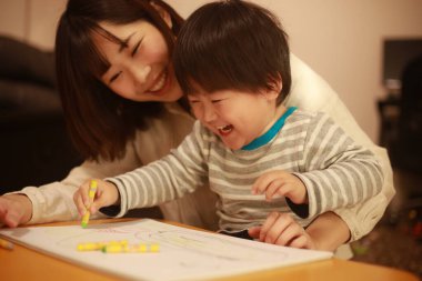 Beyaz kağıda boya kalemleri çizen genç anne ve oğul.