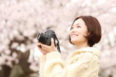 Parkta kamerası olan genç bir kadın.