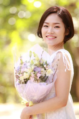 Açık havada gülümseyen güzel bir Asyalı kadının portresi.