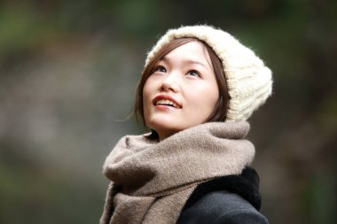 Sonbahar parkında poz veren Asyalı genç kadının portresi. 