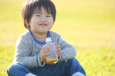 Parkta meyve suyu içen mutlu çocuk portresi