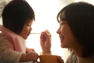 Genç anne, sevimli bebeği evde besliyor.