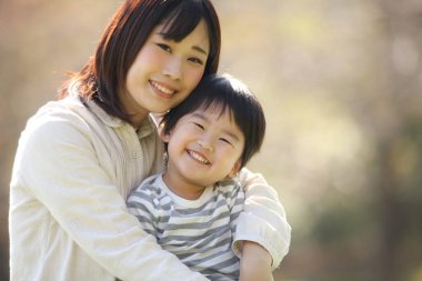 Asyalı anne oğluna sarılıyor.