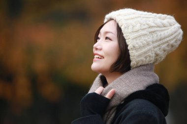 Sonbahar parkında poz veren Asyalı genç kadının portresi. 