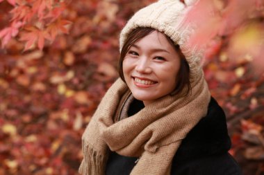 Sonbahar parkında poz veren Asyalı genç kadının portresi. 