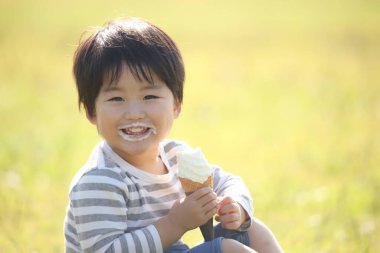 Çocuk parkta dondurma yiyor. 