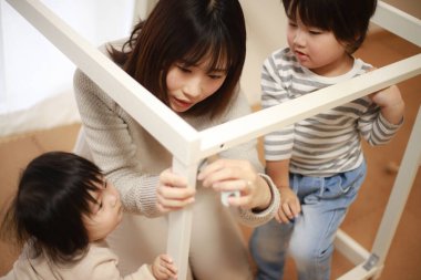 Çocuklu Asyalı kadın yeni evinde masa topluyor.