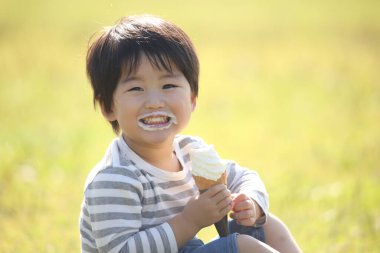 Çocuk parkta dondurma yiyor. 