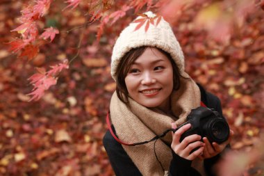 Sonbahar parkında resim çeken Asyalı genç bir kadının portresi. 