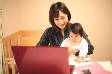 Kadın çocuğuyla birlikte evden çalışıyor.