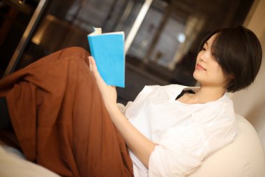 Kanepede kitap okuyan güzel bir kadın.