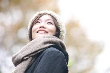 Sonbahar parkında poz veren Asyalı genç kadının portresi. 