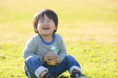 Parkta meyve suyu içen mutlu çocuk portresi