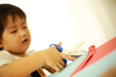 Asyalı bebek makasla oynuyor.