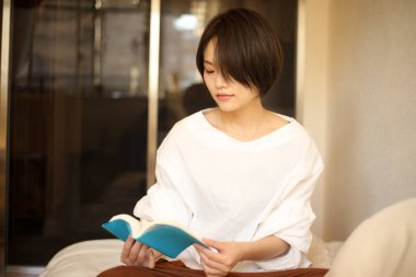 Kanepede kitap okuyan güzel bir kadın.