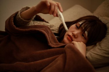 Termometresi olan genç Asyalı kadın hasta. 