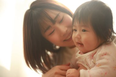 Güzel genç anne pencere ışığında kızıyla oynuyor.  