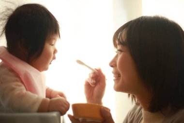 Genç anne, sevimli bebeği evde besliyor.