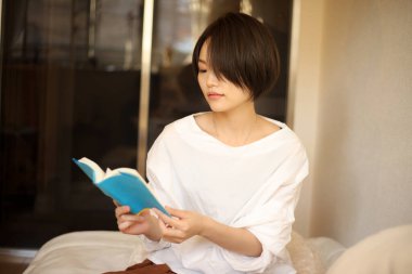 Kanepede kitap okuyan güzel bir kadın.