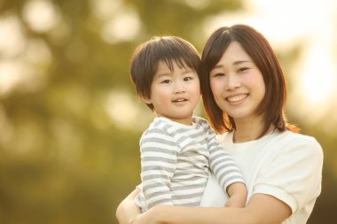 Asyalı anne oğluna sarılıyor.