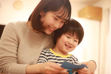 Gülümseyen Asyalı genç kadın ve küçük oğlu el kreması yapıyorlar. 