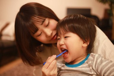 Genç anne, küçük oğlu için dişlerini fırçalıyor.