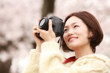 Parkta kamerası olan genç bir kadın.