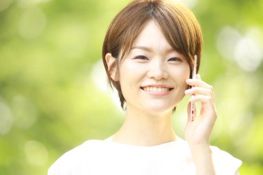 Genç Asyalı kadın cep telefonuyla konuşuyor.