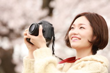 Parkta kamerası olan genç bir kadın.