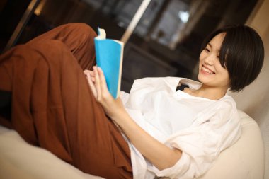 Kanepede kitap okuyan güzel bir kadın.