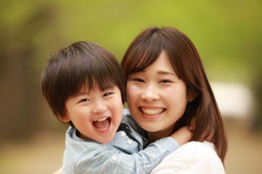 Genç Asyalı anne ve küçük oğlu parkta eğleniyorlar.  