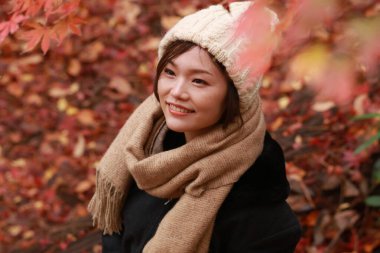 Sonbahar parkında poz veren Asyalı genç kadının portresi. 