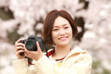 Parkta kamerası olan genç bir kadın.