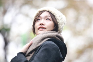 Sonbahar parkında poz veren Asyalı genç kadının portresi. 