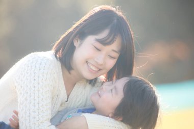 Küçük sevimli Asyalı çocuk ve annesi parkta.