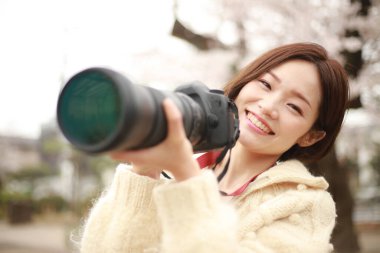 Parkta kamerası olan genç bir kadın.