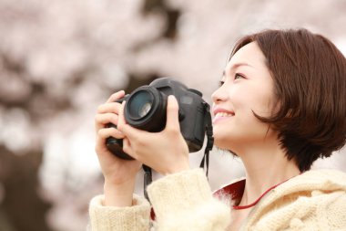 Parkta kamerası olan genç bir kadın.