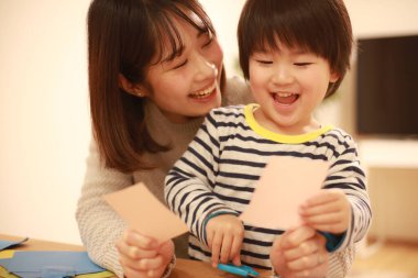 Gülümseyen Asyalı genç kadın ve küçük oğlu el kreması yapıyorlar. 