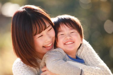 Küçük sevimli Asyalı çocuk ve annesi parkta.