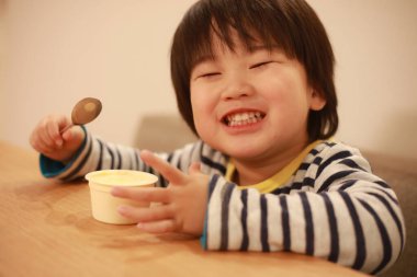 Asyalı şirin çocuk mutfakta yemek yiyor.