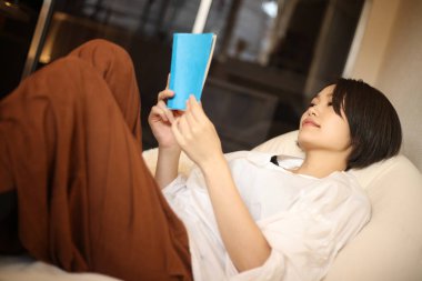 Kanepede kitap okuyan güzel bir kadın.