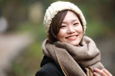 Sonbahar parkında poz veren Asyalı genç kadının portresi. 