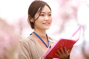 Genç Asyalı kadın parkta notlar alıyor. 