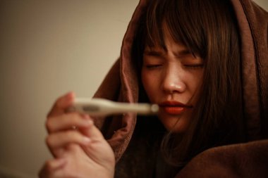 Termometresi olan genç Asyalı kadın hasta. 