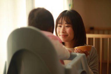 Genç anne, sevimli bebeği evde besliyor.